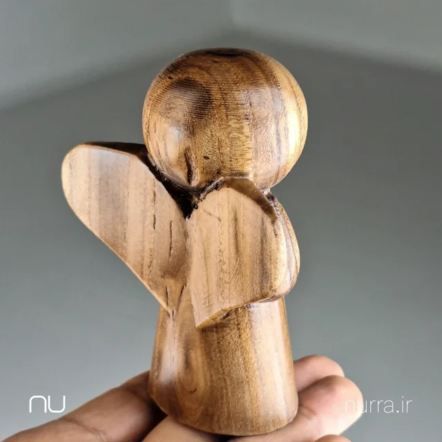 نما پشت تصویر مجسمه فرشته چوبی نورا